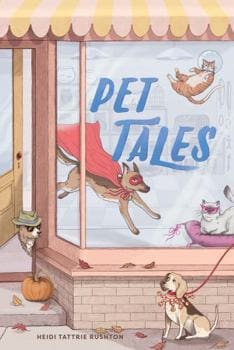 A dog in a super hero cape in a pet store window. The title is on the window. There is a dog with yellow and black patches and a red leash sitting in front of the window.